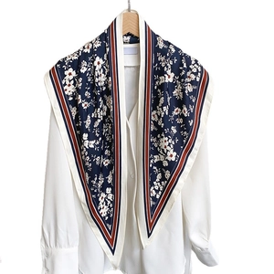 Elegant navy blue floral silk scarf with striped borders displayed on a white shirt