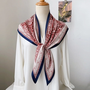 Détail d'un foulard triangle en soie à motif paisley rouge et marine sur un mannequin