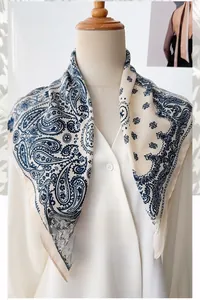 Detail of navy paisley herringbone square scarf tied on neck over a white shirt