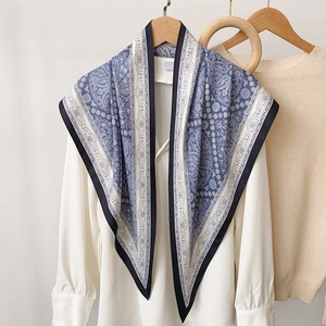 Élégant foulard en soie bleu à motif paisley porté en châle sur une chemise blanche