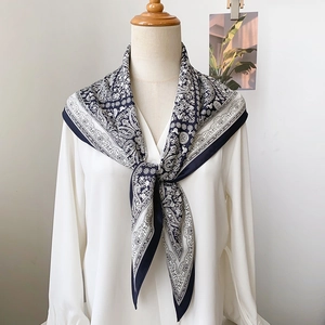 Détail du motif paisley vintage sur un foulard triangle bleu marine sur chemise blanche