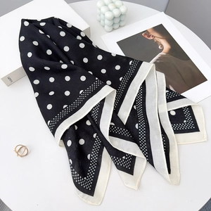 Close-up of black and white polka dot silk scarf with elegant geometric border design