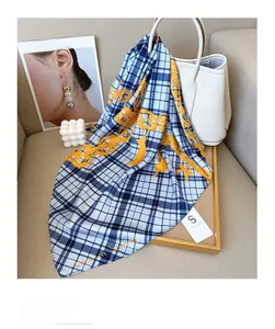 Détail d'un foulard en soie à carreaux bleus et chaîne orange sur un sac en cuir