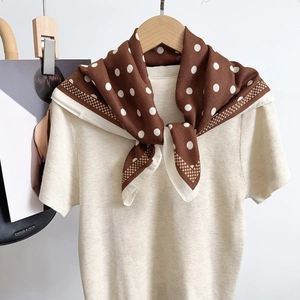Brown polka dot silk scarf tied on a knit sweater, featuring elegant white wide borders