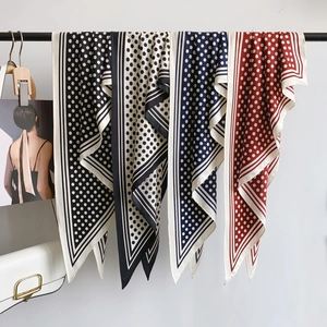Retro polka dot silk scarf in four classic colors hanging on a modern display rack