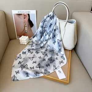 Eleganter weißer Seidenschal mit Schmetterlingsdruck an Luxustasche für das Sommerstyling