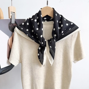 Chic black and white polka dot silk scarf paired with a beige short sleeve knit top