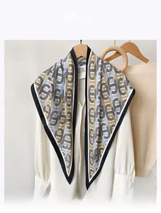 Détail d'un foulard en soie synthétique avec imprimé chaîne géométrique sur chemise blanche