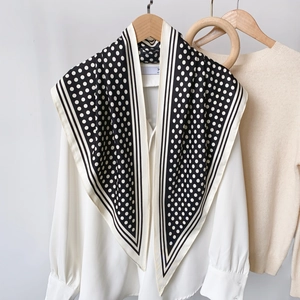 Classic black and white polka dot silk scarf on a wooden hanger with white shirt