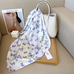 Eleganter Satin-Viereckschal mit Schmetterlingsdruck an einer Lederhandtasche