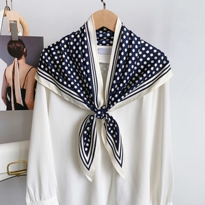Close-up of a white chiffon shirt collar with a navy polka dot silk scarf and magazine detail