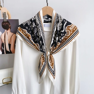 Detail of elegant patterned silk scarf styled on a white chiffon long-sleeve shirt