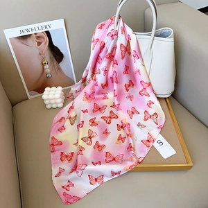 Rosa Seidenschal mit Schmetterlingsdruck an weißer Handtasche mit eleganten Requisiten