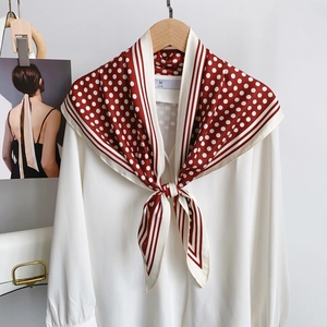 Close-up of red and white polka dot silk scarf styled as an elegant bow on a white shirt