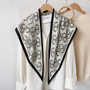 Foulard triangle à motif chaîne géométrique drapé sur chemise blanche avec cintre en bois