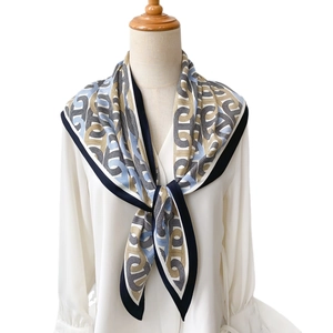Foulard en soie vintage à motif chaîne bleu marine et or noué sur un mannequin
