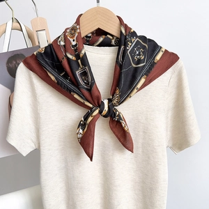 Close-up of silk scarf with equestrian horse bit print on beige knit shirt for women