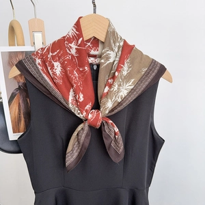 Détail d'un foulard en soie vintage aux motifs floraux rouges sur une robe noire