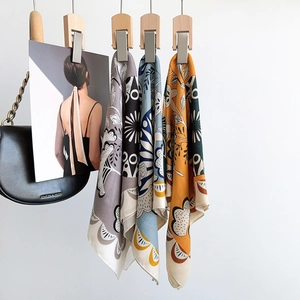 Detail showing four different patterns of square silk scarves hanging on wooden clips
