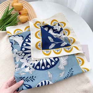Detail of blue and yellow floral silk square scarf shown on elegant minimalist wooden tray