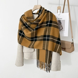 Detail of pink plaid scarf showing warm texture and stylish tassel on beige coat
