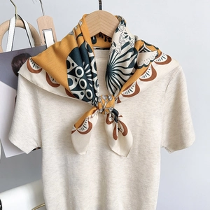 Detail of floral silk scarf tied elegantly on a cream knitted collar with mustard accents
