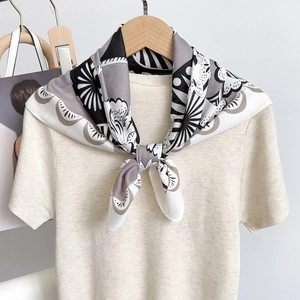 Minimalist square silk scarf with vintage floral print tied on a beige knit top