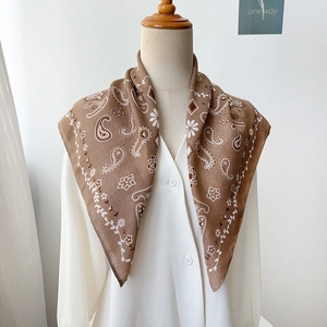 Close-up of brown paisley square scarf with vintage floral border on white shirt