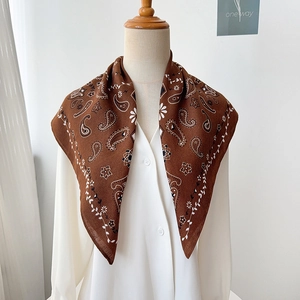 Detailed view of a brown paisley square silk scarf styled on a mannequin with white shirt