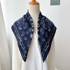 Detail of navy blue paisley silk scarf tied on a white shirt neck for a vintage look