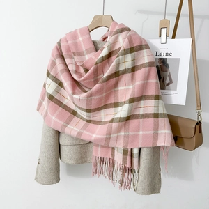 Pink and brown plaid scarf in faux cashmere with tassels styled on a beige coat