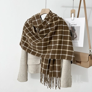 Detailed close-up of brown and white plaid knit scarf with soft tassel edges