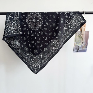 Carré de soie noir classique avec motif Paisley blanc suspendu sur un support de vente