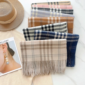Detail showing various colors of plaid cashmere-like scarves with tassel edges