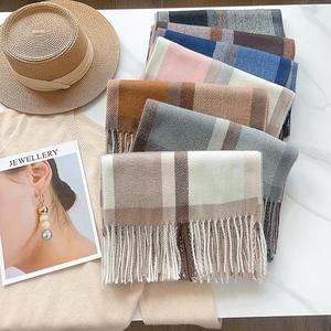 Flat lay of colorful plaid scarves featuring tassel details and soft cashmere-like texture