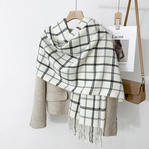 Classic black and white plaid scarf with long tassels over a brown wool blazer