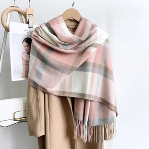 Close-up of pink and grey plaid scarf with soft fringe details over a beige coat