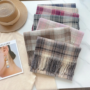 Flat lay of soft plaid cashmere-feel scarves with tassels in various warm neutral tones