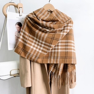 Classic plaid imitation cashmere scarf in camel with tassels hung on a tan coat