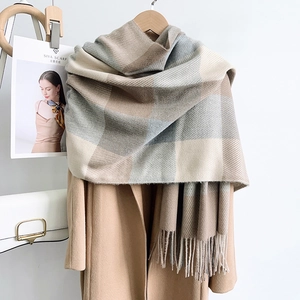 Détail d'une écharpe à carreaux douce avec franges et manteau aux tons morandi