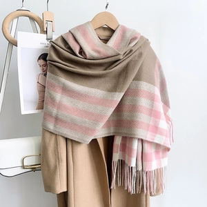 Détail de l'écharpe à carreaux rose et beige avec franges sur un manteau beige