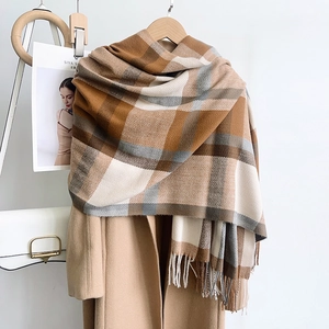 Plaid cashmere-like scarf with fringe in caramel and gray colors over tan coat