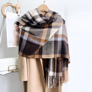 Classic blue and brown plaid tassel scarf shown elegantly on a wooden hanger with a coat