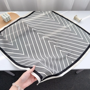 Detailed view of striped silk scarf texture and elegant black and white geometric print