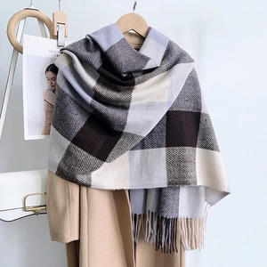 Détail d'une écharpe à carreaux et franges associée à un manteau en laine beige