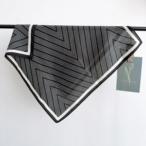 Minimalist black and white zigzag silk scarf with border displayed in hanging view
