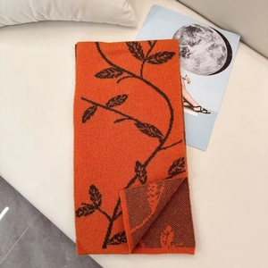 Winterlicher orangefarbener Strickschal mit schwarzen Blattmustern aus weichem Stoff