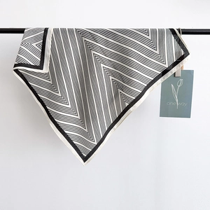 Detail of black and white striped silk scarf displayed on a metal rack with a gift card