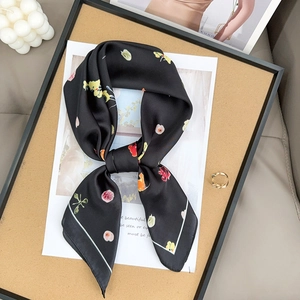 Vista dettagliata di un foulard in seta floreale a fiocco con candela e anello d'oro su vassoio