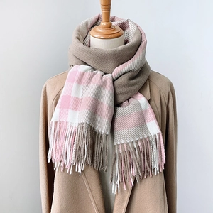 Écharpe à carreaux rose et gris avec franges portée sur un manteau de laine